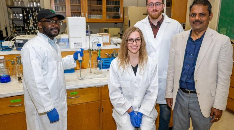 Four people stand together in a laboratory 